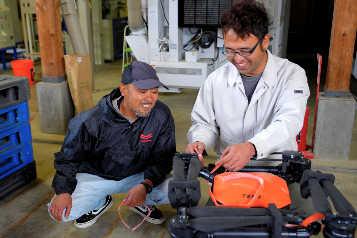 ドローンを手入れする草薙さんと田村さん